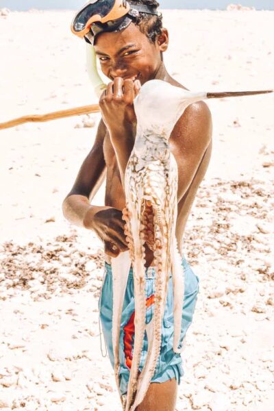 Madagascan boy with octopus he caught on beach