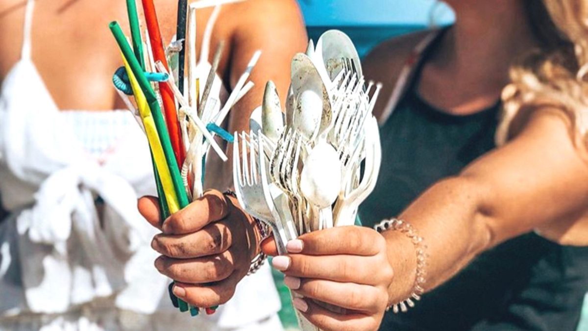 girls holding plastic straws and cutlery found on the beach