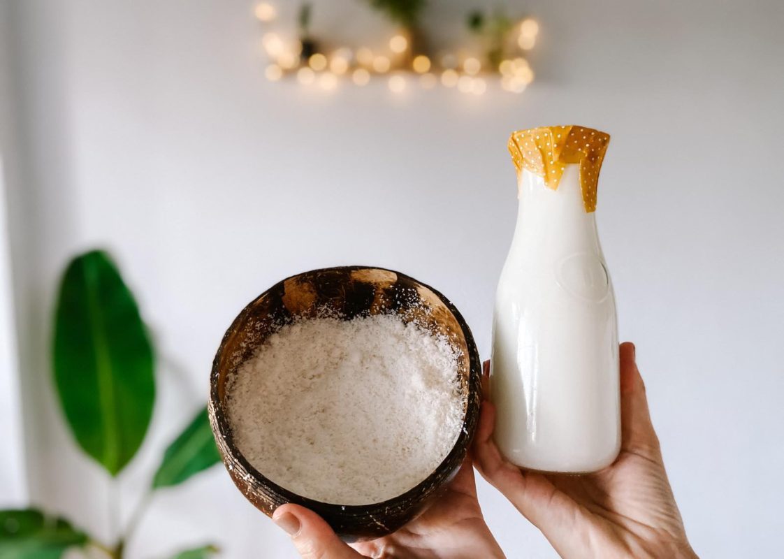 coconut milk in a glass jar with a bowl of coconut pulp