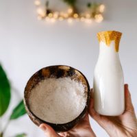 coconut milk in a glass jar with a bowl of coconut pulp