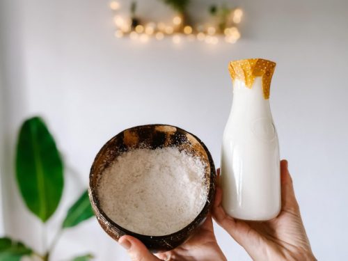 coconut milk in a glass jar with a bowl of coconut pulp