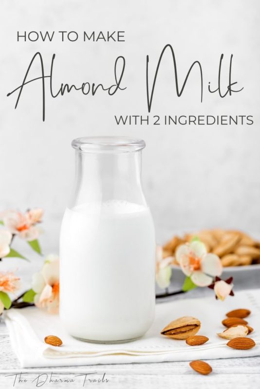 almonds and flowers around a jar filled with almond milk