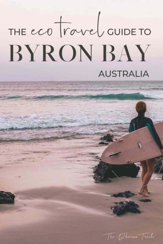 surfer at wategos bay with text overlay the eco travel guide to byron bay