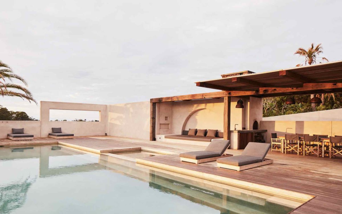 Luxury property with minimalist style decor, low deck chairs next to a luxury pool