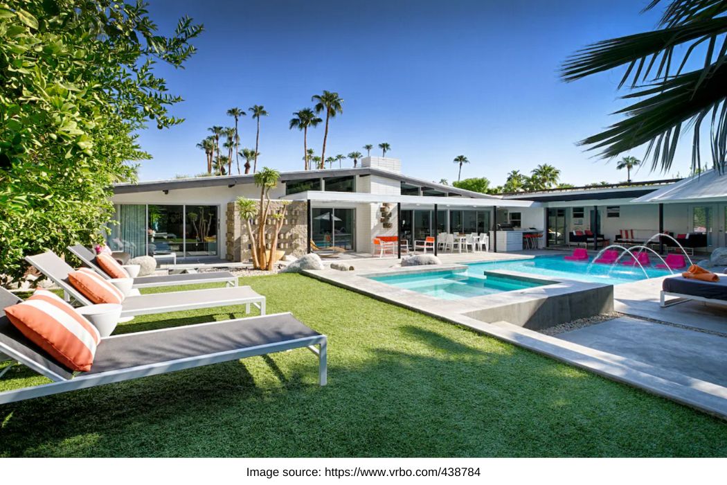 outdoor area with pool and home in background with palm trees