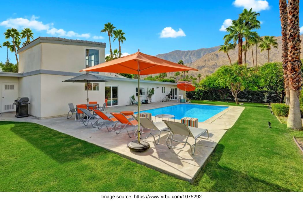 pool with an orange umbrella and mid century home with palm springs and mountains