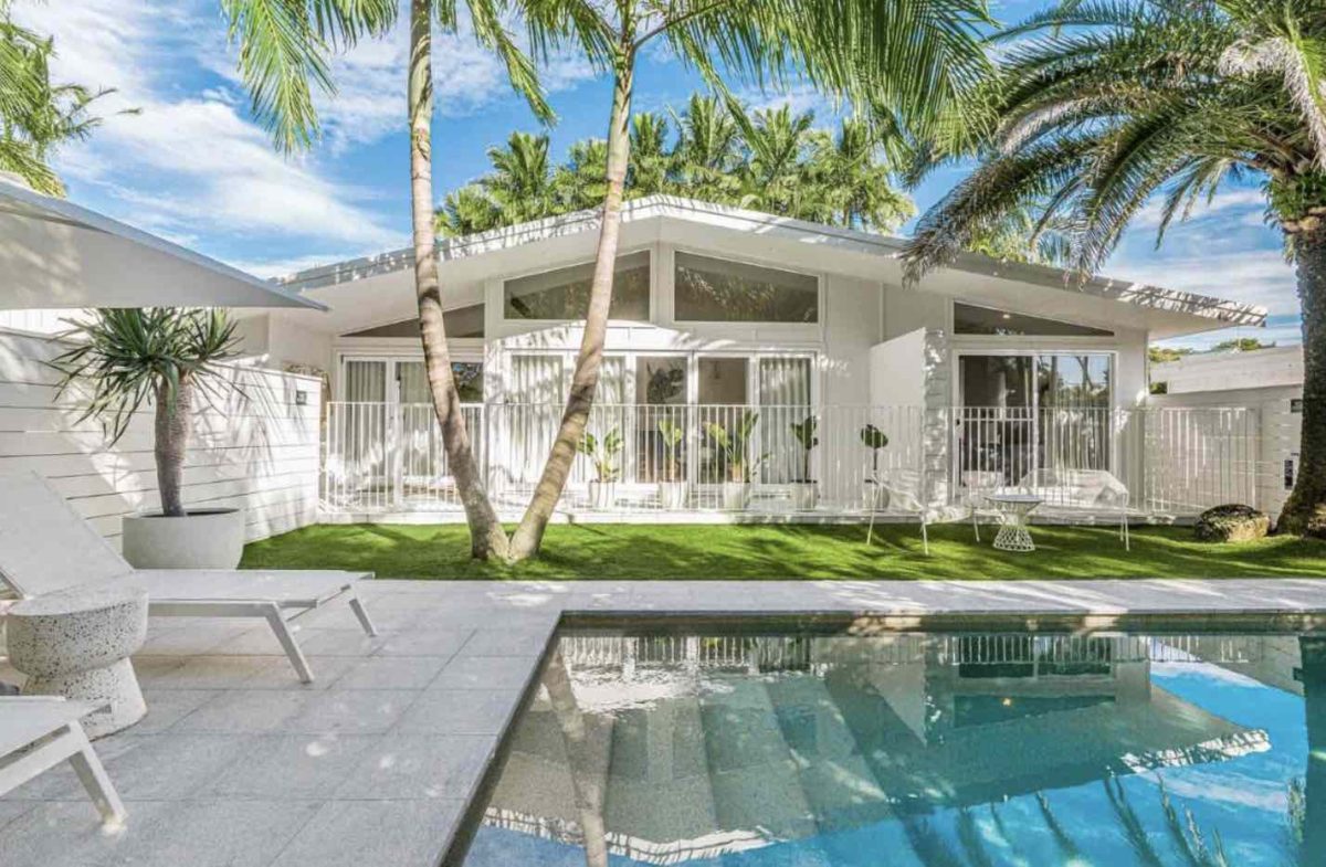 modern white house surrounded by palm trees and a pool