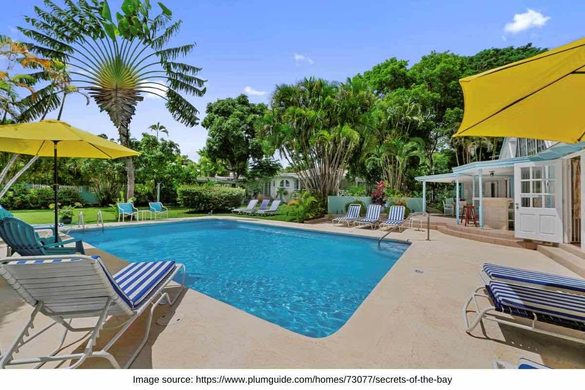villa pool and yellow umbrellas set in a lush garden in barbados